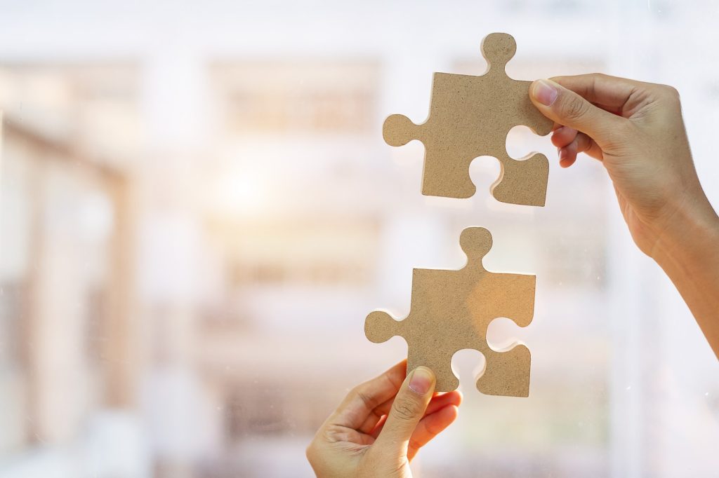 Woman hands connecting couple puzzle piece against sunrise effect